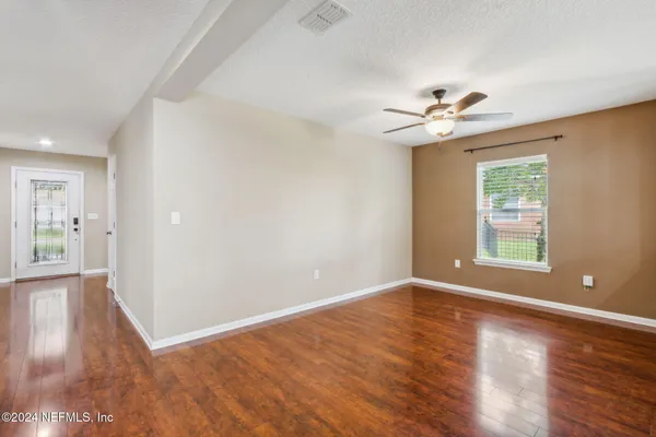 a view of an empty room with a window and wooden floor