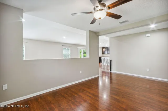 a view of empty room with wooden floor and fan