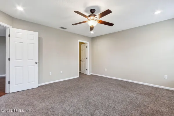 an empty room with closet and a ceiling fan