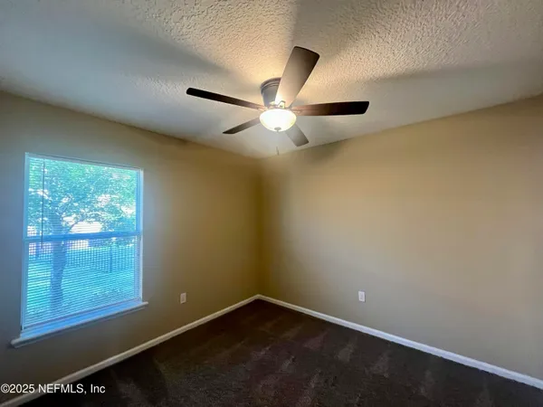 an empty room with windows and fan