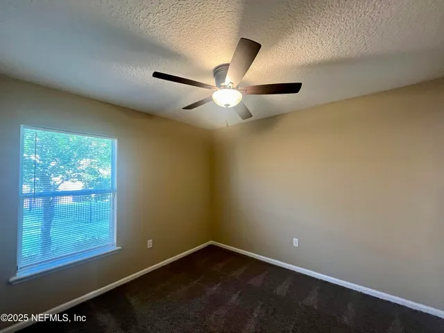 an empty room with windows and fan
