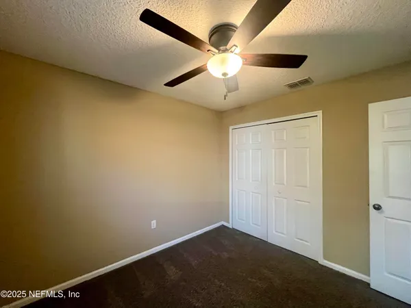 an empty room with a ceiling fan and a window