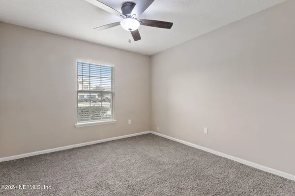 an empty room with a window and a fan