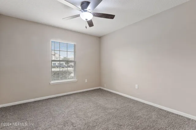 an empty room with a window and a fan