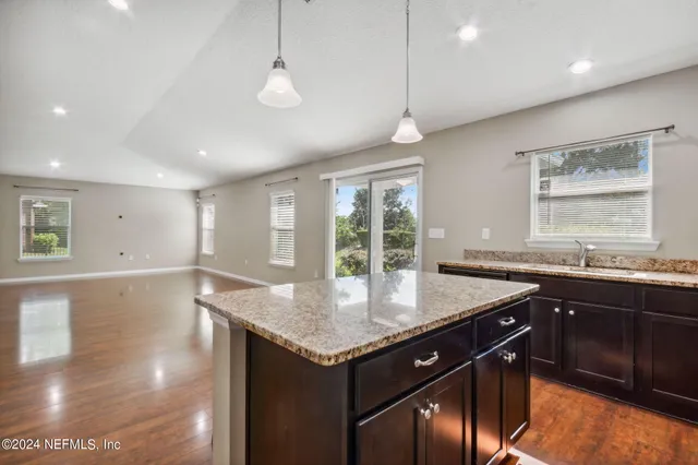 a kitchen with granite countertop a sink window and cabinets