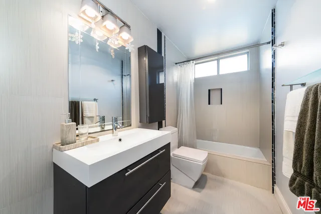 a bathroom with a sink a toilet a mirror and shower