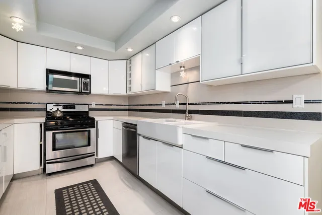 a kitchen with granite countertop white cabinets and stainless steel appliances