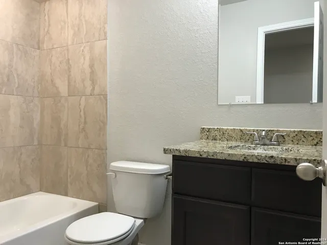 a bathroom with a granite countertop sink and a toilet