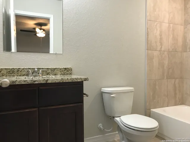 a bathroom with a granite countertop toilet sink and mirror