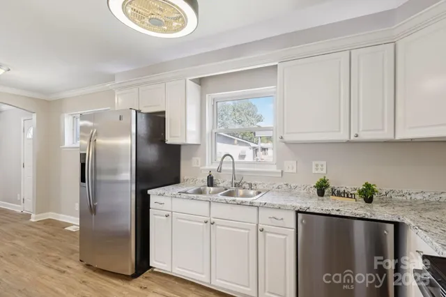 a kitchen with stainless steel appliances granite countertop a refrigerator a sink a stove and island with wooden floor