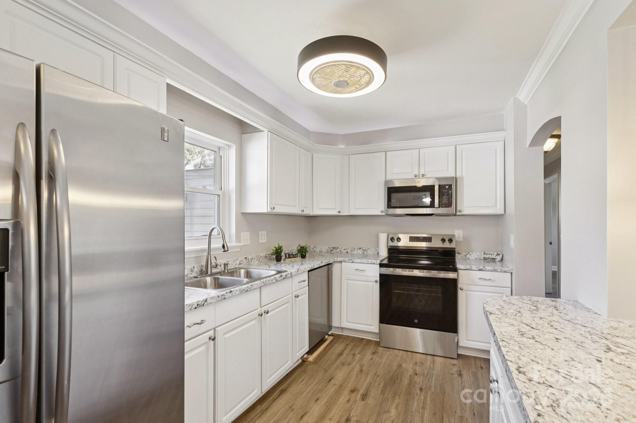 1024 Old Mountain View Road Mount Holly, NC 28120 - Photo 9 of 41 a kitchen with stainless steel appliances granite countertop a refrigerator a stove top oven a sink and dishwasher with wooden floor