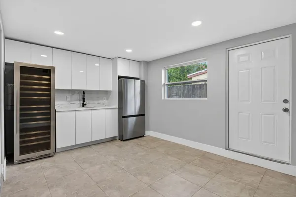 a view of kitchen with refrigerator cabinets and window