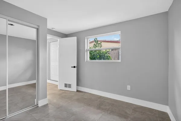 a view of an empty room with closet and a window