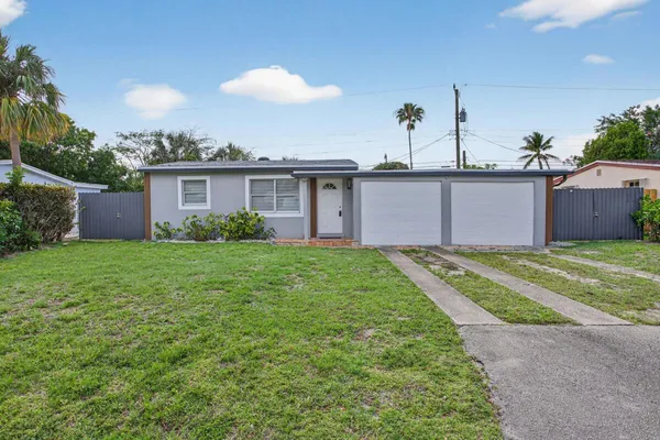 a front view of house with yard and trees in the background