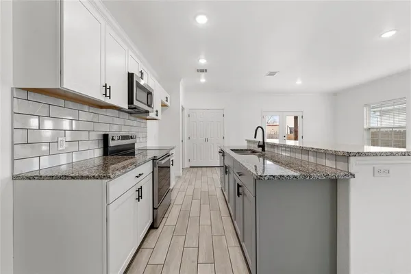 a kitchen with stainless steel appliances granite countertop a sink a stove and cabinets