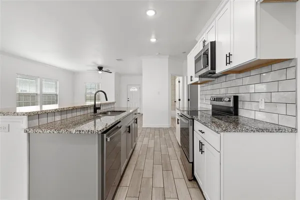 a kitchen with stainless steel appliances granite countertop a sink stove and cabinets