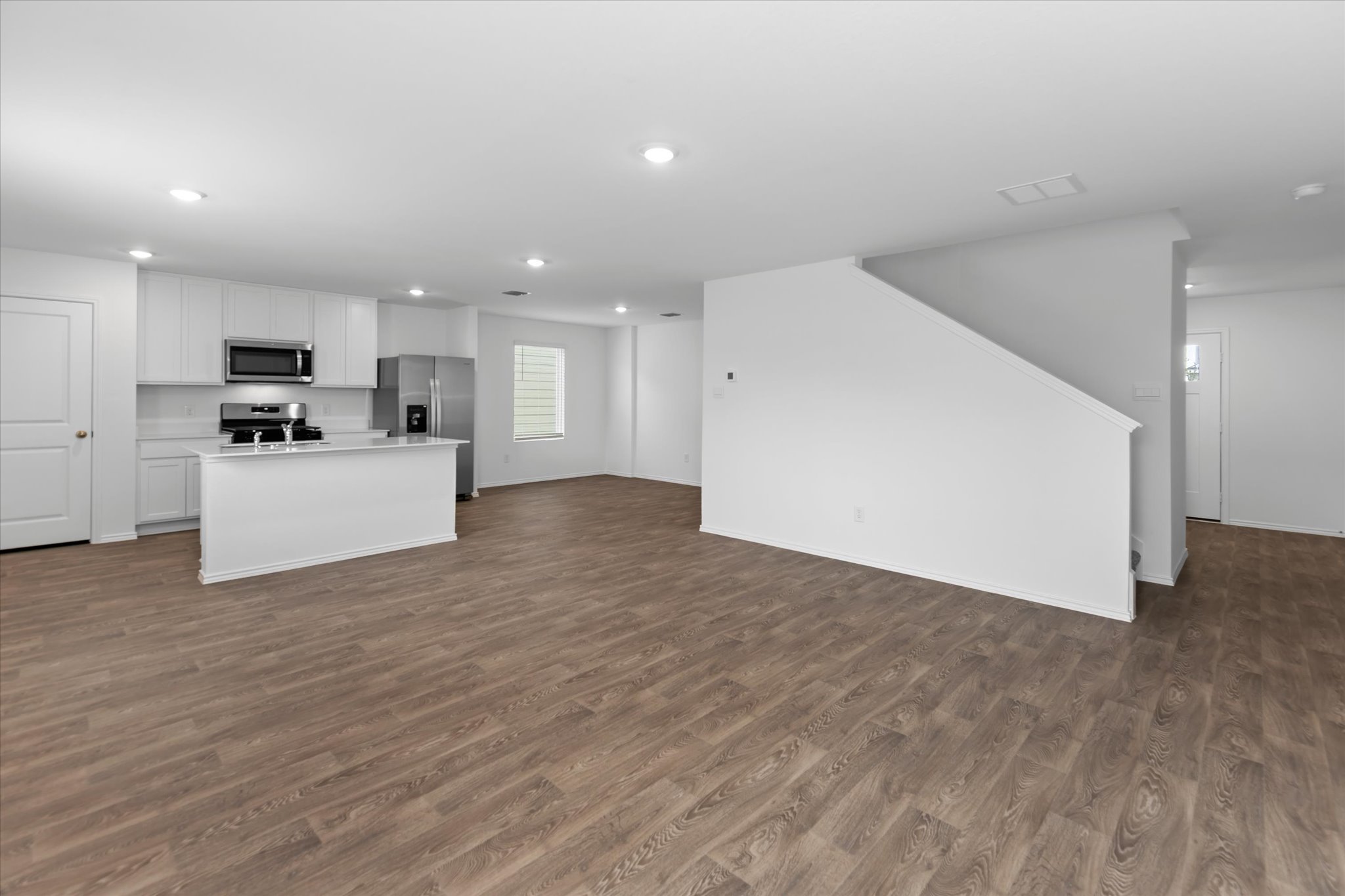 456 Sandringham Loop Kyle, TX 78640 - Photo 27 of 40 An open-concept living space integrates a modern kitchen, featuring recessed lighting and durable wood-look flooring.