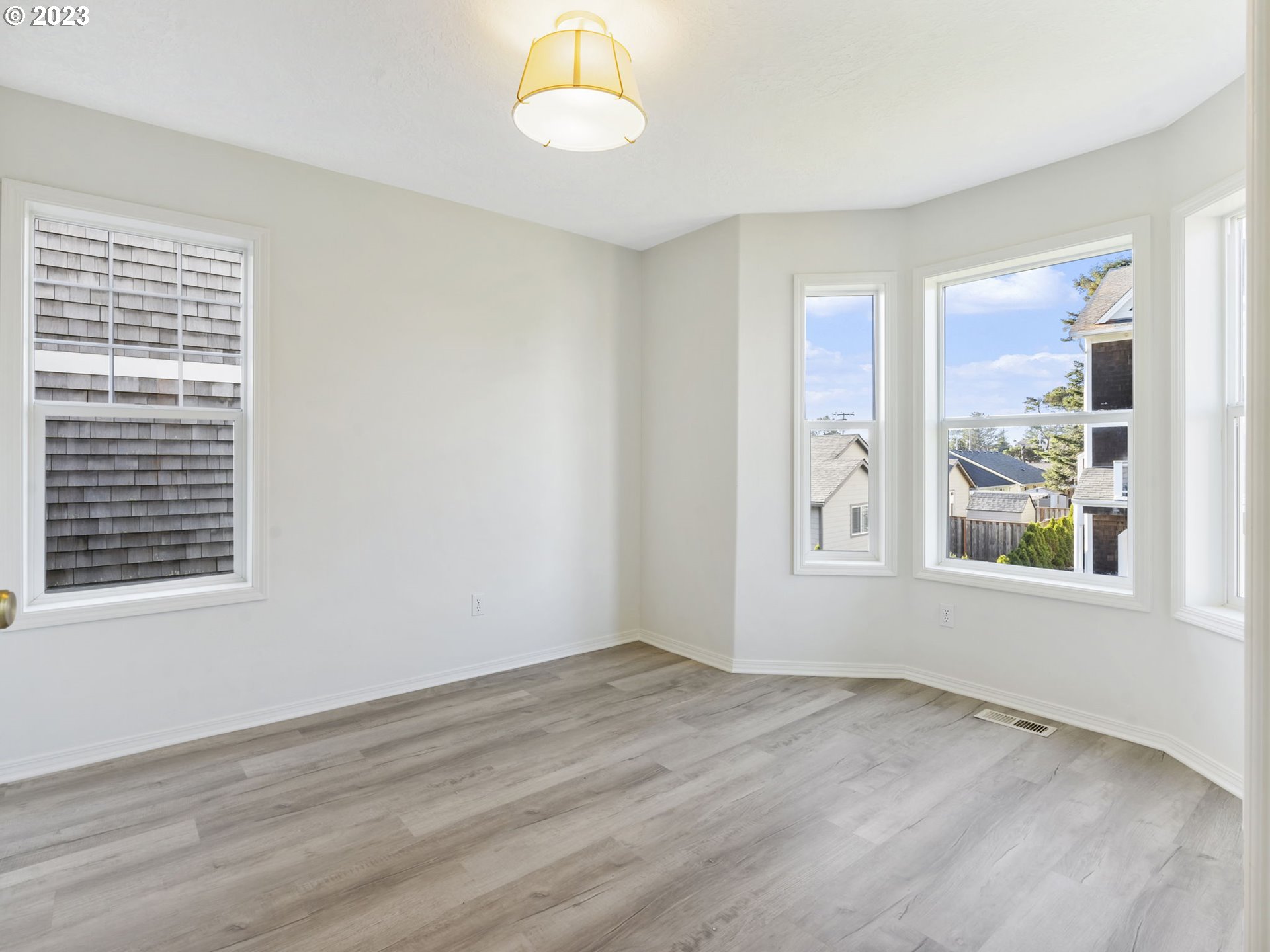 940 Necanicum Drive Seaside, OR 97138 - Photo 8 of 23 an empty room with wooden floor and windows