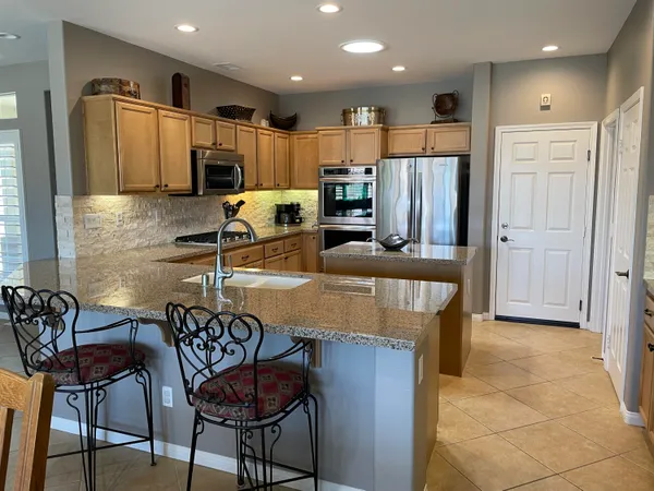 a kitchen with stainless steel appliances granite countertop a table chairs and a refrigerator
