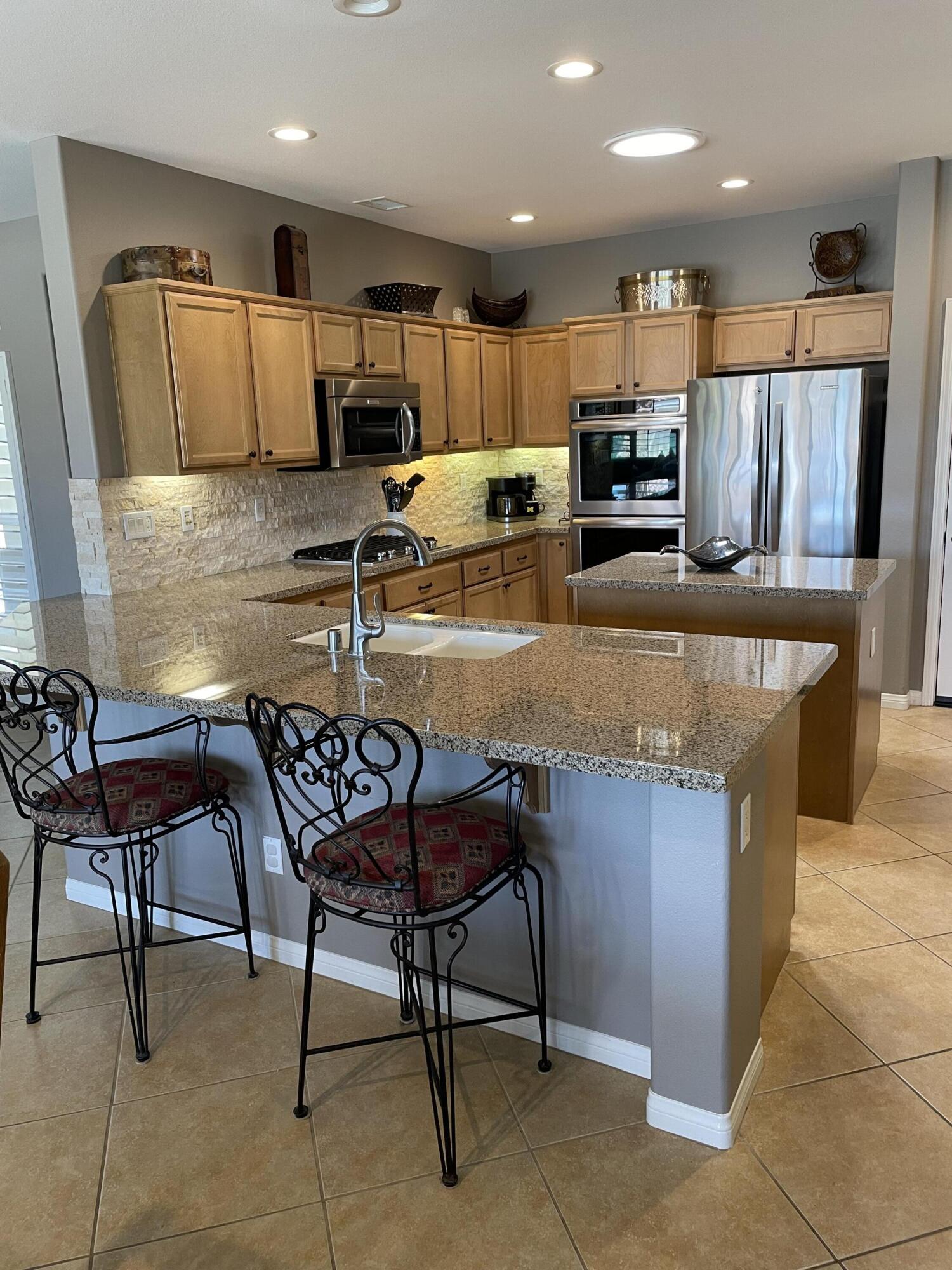 60880 Azul Court La Quinta, CA 92253 - Photo 9 of 33 a kitchen with kitchen island granite countertop wooden cabinets and a refrigerator