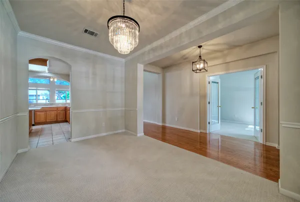 a view of a hallway with wooden floor and a chandelier