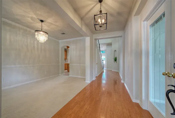 a view of a hallway with wooden floor and a chandelier