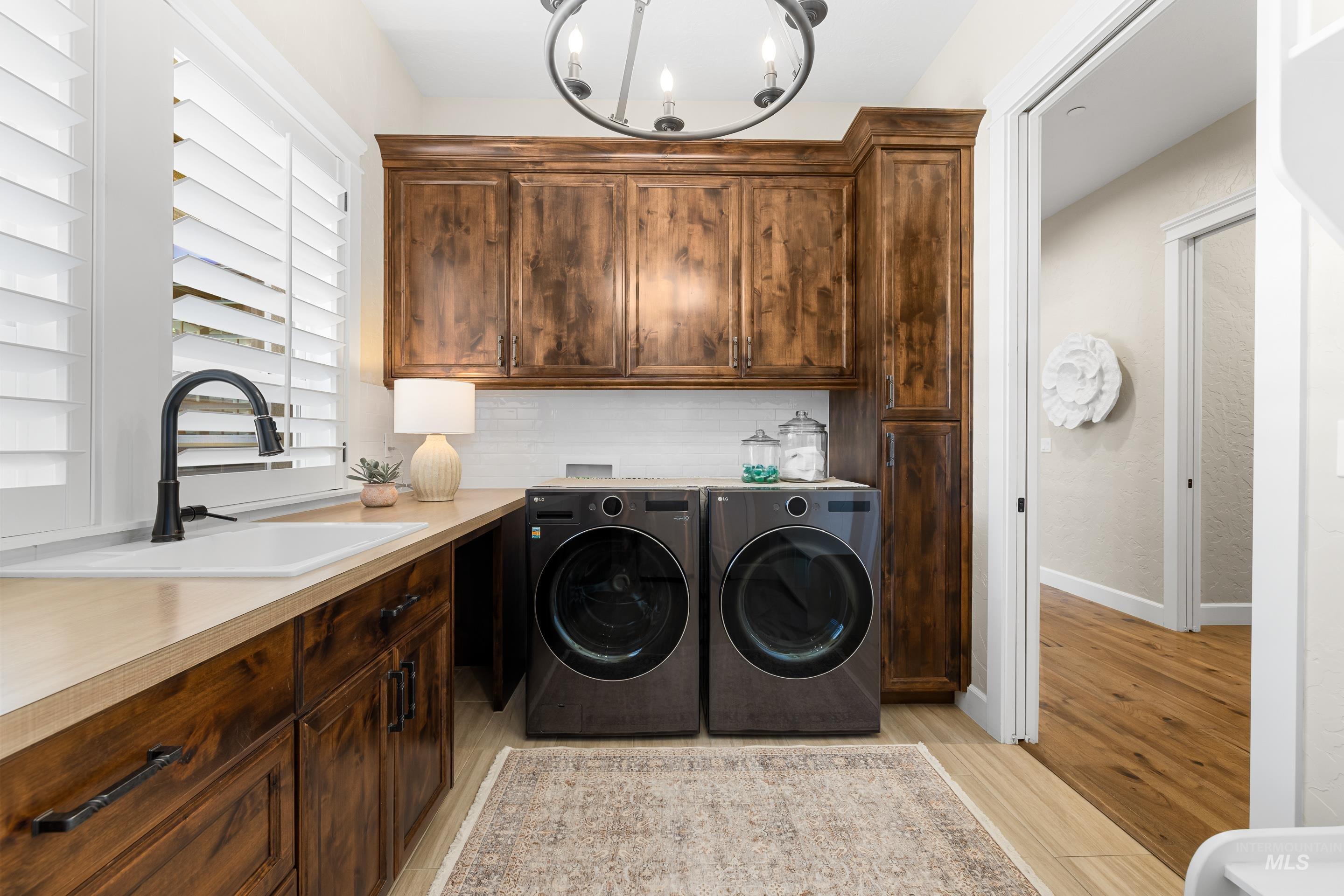9819 Foothill Road Middleton, ID 83644 - Photo 34 of 49 Laundry room featuring independent washer and dryer, cabinet space, a chandelier, and light wood finished floors