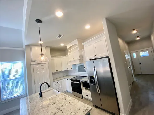 a kitchen with stainless steel appliances granite countertop a refrigerator a sink a stove and a refrigerator