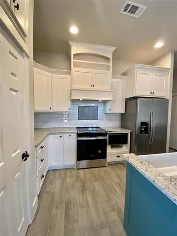 a large kitchen with stainless steel appliances granite countertop a stove a sink and a refrigerator