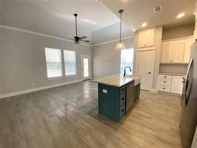 a kitchen with stainless steel appliances granite countertop a sink a stove a refrigerator cabinets and wooden floor