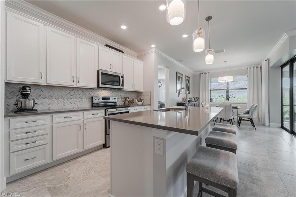 19855 Beverly Park Road Estero, FL 33928 - Photo 3 of 42 a kitchen with granite countertop a stove a sink a dining table and chairs