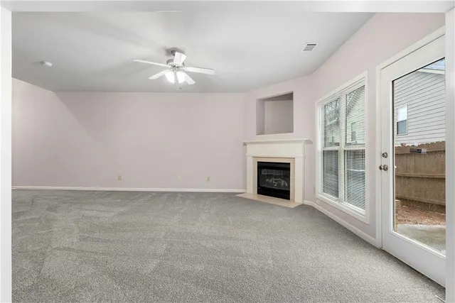 a view of an empty room with chandelier fan and fire place