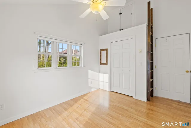 a view of an empty room with wooden floor and a window