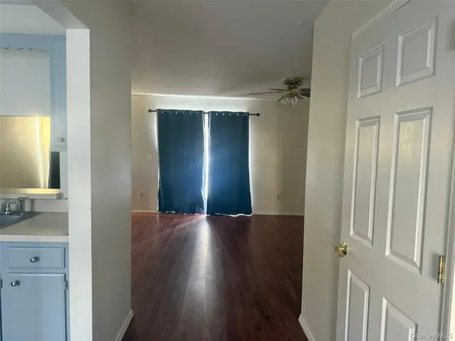 a view of a hallway with wooden floor and a bathroom
