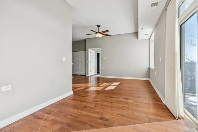 a view of empty room with wooden floor and fan