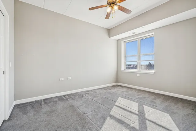 an empty room with a chandelier fan and windows