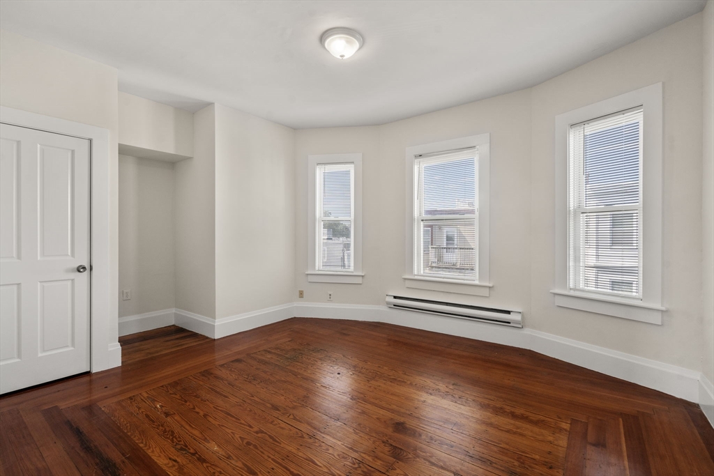 27 Buttonwood Street Boston, MA 02125 - Photo 8 of 12 a view of an empty room with wooden floor and a window
