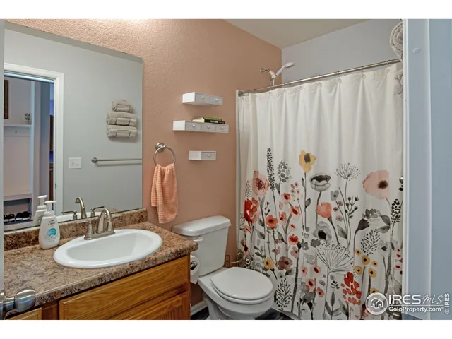 a bathroom with a granite countertop sink a toilet a mirror and shower curtain