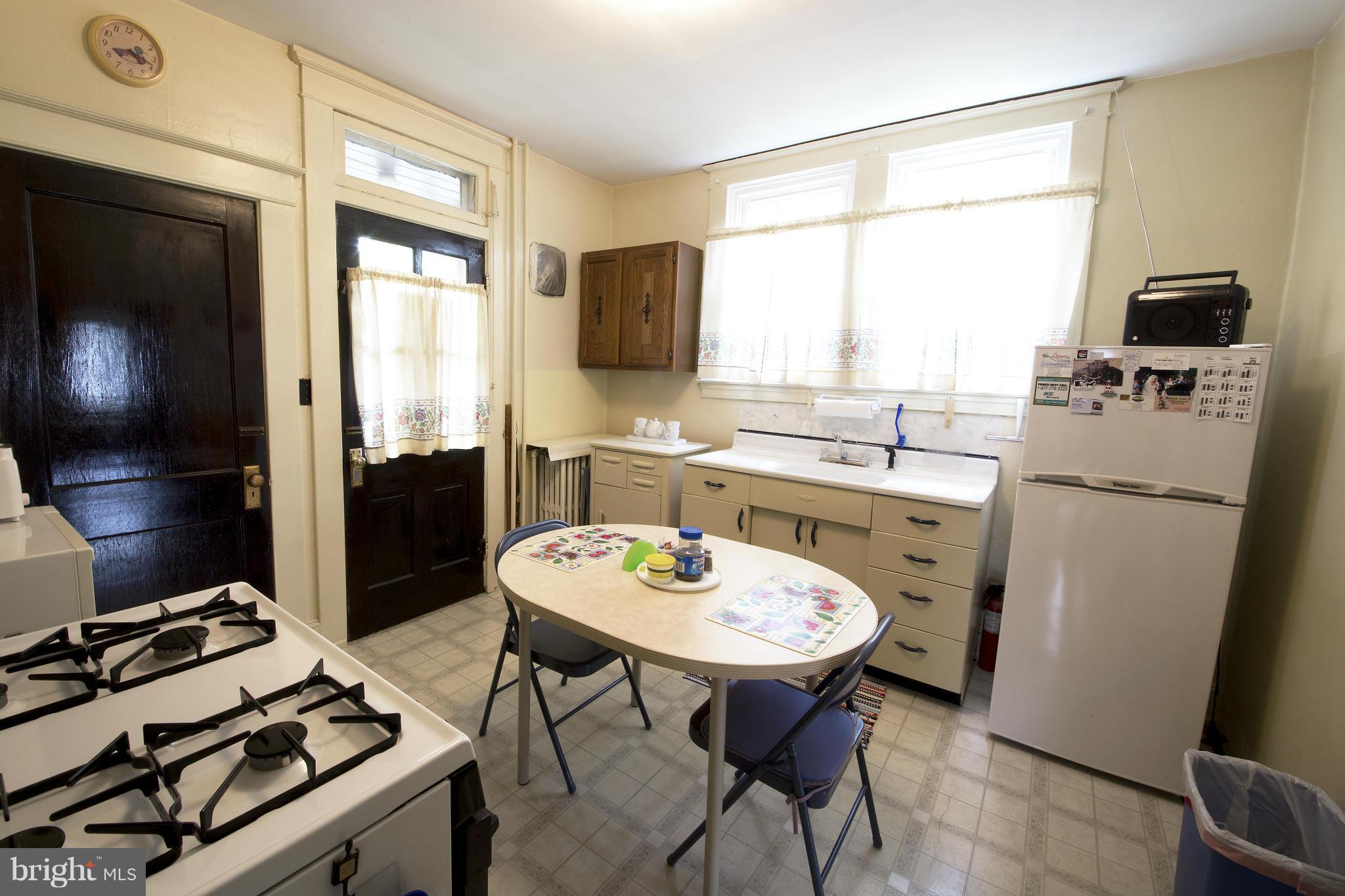 4502 Ridge Avenue Halethorpe, MD 21227 - Photo 6 of 24 a kitchen with a dining table chairs and a refrigerator