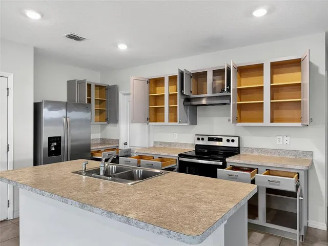 a kitchen with granite countertop a sink stove and refrigerator