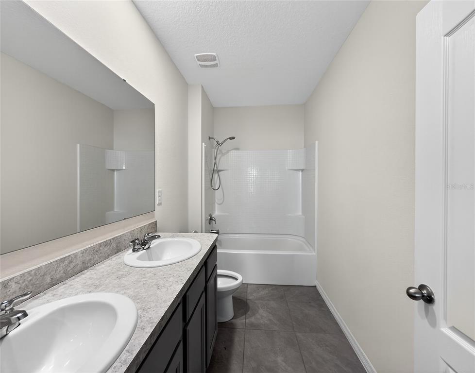 2597 Shamrock Street Tavares, FL 32778 - Photo 21 of 57 a bathroom with a granite countertop sink a toilet and shower