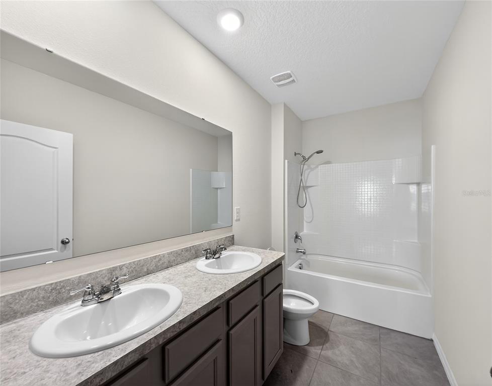 2597 Shamrock Street Tavares, FL 32778 - Photo 45 of 57 a bathroom with a granite countertop sink toilet a shower and a mirror