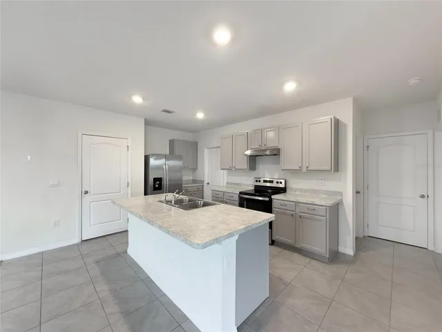 a kitchen that has a lot of white cabinets and stainless steel appliances