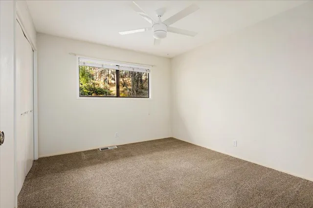 an empty room with windows and ceiling fan view