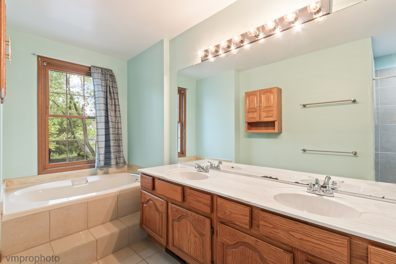 4549 Topaz Drive Hoffman Estates, IL 60192 - Photo 9 of 20 a bathroom with a granite countertop double vanity sink a large mirror a bathtub and next to a window