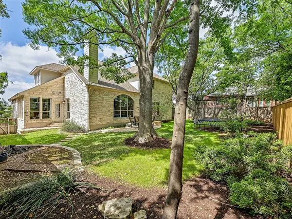 a backyard of a house with plants and large tree