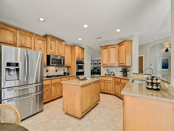 a kitchen with stainless steel appliances granite countertop a refrigerator a stove top oven a sink a stove and cabinets