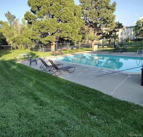 a view of a yard with swimming pool and trees in the background