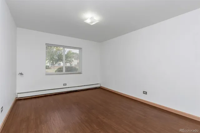 an empty room with wooden floor and window