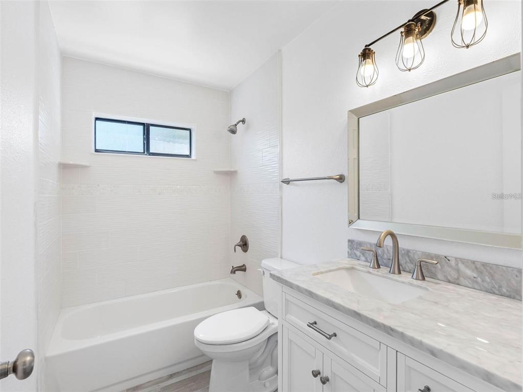 562 Johns Pass Avenue Madeira Beach, FL 33708 - Photo 25 of 51 a bathroom with a granite countertop sink a toilet and bathtub
